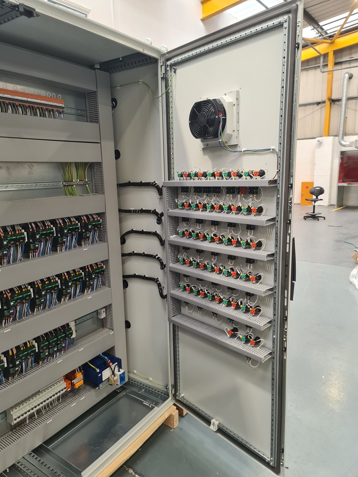 Door open on one bay, showing the mimic plate with run and trip lamps and hand/off/auto selectors for each motor