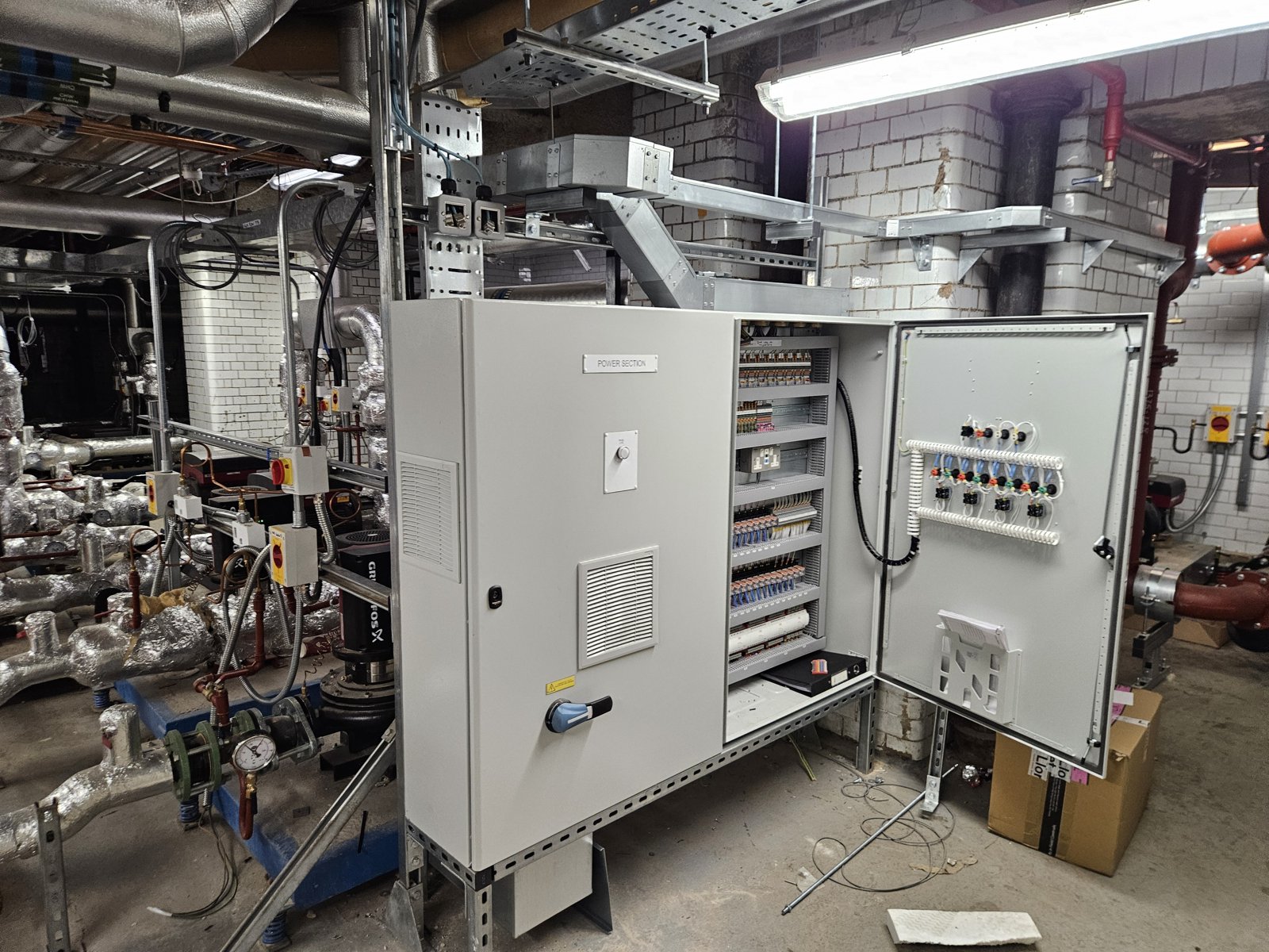 A wall-mounted outstation panel with the door open during commissioning